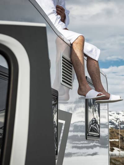 man relaxing on top of his Brinkley RV in the mountains living a luxury rv lifestyle
